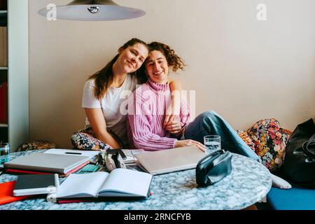 Porträt glücklicher junger Freundinnen, die zu Hause sitzen Stockfoto