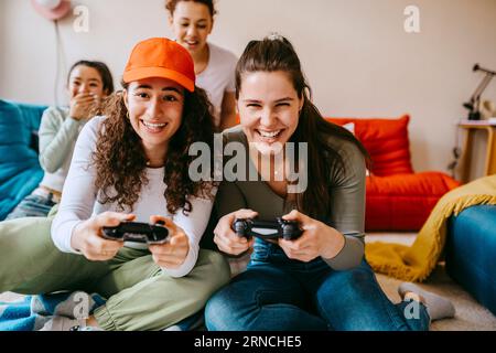 Junge Freundinnen, die zu Hause Videospiele genießen Stockfoto