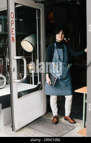 Porträt einer weiblichen Ladenbesitzerin, die am Eingang steht Stockfoto