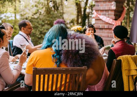 Rückansicht der LGBTQ-Freunde, die während der Dinnerparty im Hinterhof zusammen sitzen Stockfoto