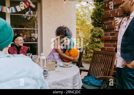LGBTQ-Freunde, die sich bei einer Dinnerparty im Hinterhof umarmen Stockfoto