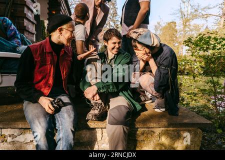 Glückliche Freunde der LGBTQ-Gemeinschaft, die zusammen genießen, während sie an sonnigen Tagen auf der Veranda sitzen Stockfoto