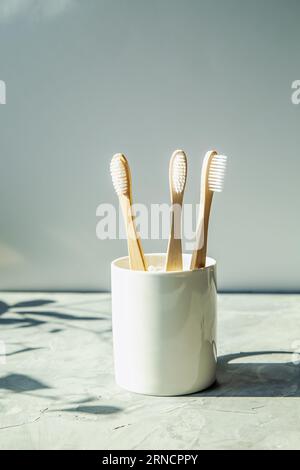 Natürliche Bambuszahnbürsten im Glas auf hellem Hintergrund. Ökologische Holzzahnbürsten, Kopierraum. Stockfoto