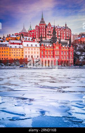 Stockholm, Schweden. Mariaberget und Sodermalm im Winter. Wunderschöner Himmel in Orange, Violett und Rosa bei Sonnenuntergang, reflektiert im gefrorenen Wasser des Mala-Sees Stockfoto