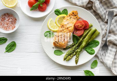 Gebackener köstlicher Lachs, grüner Spargel mit Gemüse auf dem Teller Stockfoto