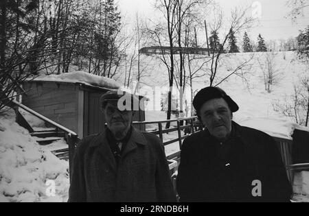 Heute 03 - 3 - 1974: Sie fanden ihren Platz vor zwölf Jahren zogen John und Pål von der Stadt bis zum Fluss. Die Stadt wurde ihnen zu schwer. Sie bauten sich in den Skauen Hütten und bekamen dafür ein Angelbecken und einen Badeplatz. Die beiden alten Menschen haben ein unangenehmes Leben geführt, aber jetzt haben sie einen Ort gefunden, wo Frieden herrscht und sie können ihre eigenen Herren sein. Sie leben von doppelter kommunaler Gnade. Die Kabine befindet sich an der Grenze zwischen Oslo und Bærum. Sie sammeln Wasser in einem Eimer direkt aus der Lysakerelva. Ein schönes Leben, denken beide. John (rechts) und Pål sind en Stockfoto