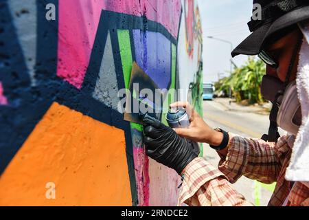 (160515) -- NAKHON SAWAN, 15. Mai 2016 -- Ein Straßenkünstler spritzt am 15. Mai 2016 Farbe auf seine Graffiti-Arbeit außerhalb einer lokalen Abwasserbehandlungsanlage in der Stadt Nakhon Sawan in Zentralthailand. Mehr als sechzig Straßenkünstler aus ganz Thailand wurden vom 13. Bis 15. Mai von der Stadtverwaltung zum Nakhon Sawan Street Art Project eingeladen. Innerhalb von drei Tagen ist es den Künstlern gelungen, die leeren Außenwände einer lokalen Abwasserbehandlungsanlage in eine Graffiti-Galerie zu verwandeln, die sich über etwa vierhundert Meter erstreckt.) THAILAND-NAKHON SAWAN-POP KULTUR-STREET ART-GRAFFITI Stockfoto