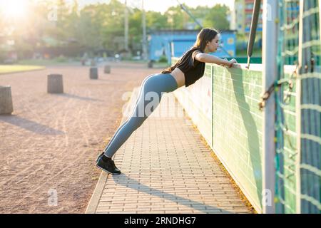 Junge Frau in Sportbekleidung, die im Stadion Gymnastik macht Stockfoto