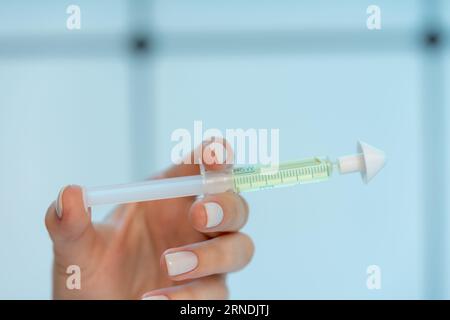 Junge Frau, die eine Spritze mit intranasaler Medizin in der Hand hält Stockfoto