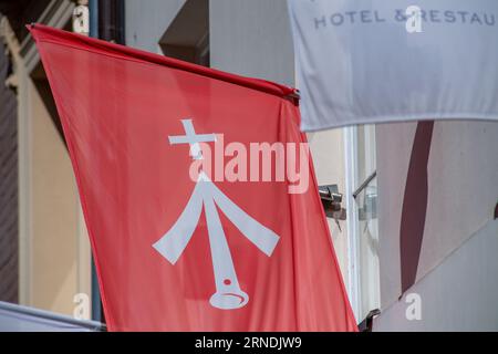 1. September 2023, Mecklenburg-Vorpommern, Stralsund: Eine Flagge mit dem Wappen der Stadt Stralsund hängt an einem Hotel in der Altstadt. Stralsund wird als vierte Stadt in Mecklenburg-Vorpommern ab dem 01.09.2023 eine Übernachtungssteuer einführen. Die Übernachtungssteuer beläuft sich auf fünf Prozent des Nettopreises für Übernachtungen (ohne Verpflegung) in Beherbergungsbetrieben und dient der allgemeinen Haushaltsfinanzierung der Hansestadt. Beherbergungsbetriebe im Sinne dieses Übernachtungssteuergesetzes umfassen insbesondere Hotels, Pensionen, Privaträume, Camping und Mob Stockfoto