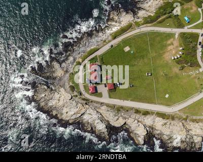 Ein Blick aus der Vogelperspektive auf das Beavertail Lighthouse Museum und die Meereswellen, die auf die felsige Küste in Jamestown, Rhode Island, stürzen Stockfoto