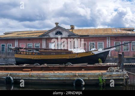 Alte hölzerne Pier, ein Segelschiff liegt neben einem schwimmenden Steg Hausboot Stockfoto
