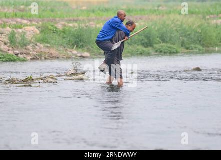 China: blinder und armloser Bauer bestellt gemeinsames Feld SHIJIAZHUANG, 31. Mai 2016 -- Jia Wenqi (R) trägt seinen Freund Jia Haixia in einem Fluss im Yeli Village im Jingxing County, nordchinesische Provinz Hebei, 31. Mai 2016. Der 55-jährige, sehlose Jia Haixia und der 54-jährige, armlose Jia Wenqi verbrachten 14 Jahre damit, ein Ödland in eine Oase zu verwandeln. (Zkr) CHINA-HEBEI-BLIND MAN AND ARMLESS MAN-TREE PLANTING(CN) ZhuxXudong PUBLICATIONxNOTxINxCHN China blind and Armloser Bauer order Common Field Shijiazhuang Mai 31 2016 Jia Wenqi r trägt seinen Freund Jia Haixia in einem Fluss im Yeli Village von Jingxi Stockfoto