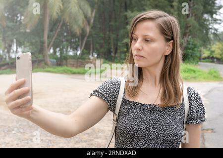 Eine Touristenfrau nimmt ein Selfie vor dem Hintergrund von Palmen und Sand. Urlaub und Tourismus, Erholung Stockfoto