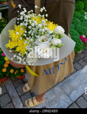 Eine junge Frau draußen mit einem lebhaften und bunten Blumenstrauß in den Händen Stockfoto