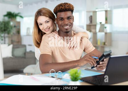Glückliches gemischtes junges Paar berechnet Inlandsrechnungen Stockfoto
