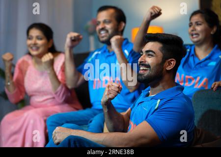 Side View Shoot of Group of Family member Shooting as India to Support Indian Cricket Team while watching on tv at Home - Konzept von energiegeladenen Fans Stockfoto