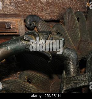 Detail des aus dem 12. Jahrhundert stammenden Bronzeschutzes an der Nordtür der Kathedrale von Durham. Eine Schlange isst das Bein eines Mannes. Der Entwurf des Klopfers basiert auf dem „Hellmouth“, einem mittelalterlichen Bild des Eintritts in die Hölle durch die Öffnung eines Tieres. Der komplette Klopfer zeigt einen Löwen, dessen Mähne einen Halo bildet, der einen Mann verschlingt. Die Beine des Mannes ragen auf beiden Seiten des Löwenmauls hervor und werden von Schlangen gefressen. Stockfoto