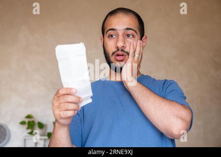 Junger bärtiger Rüde, der mit Gefühlen im Gesicht im Wohnzimmer rezitiert Stockfoto