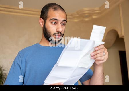 Junger bärtiger Rüde, der mit Gefühlen im Gesicht im Wohnzimmer rezitiert Stockfoto