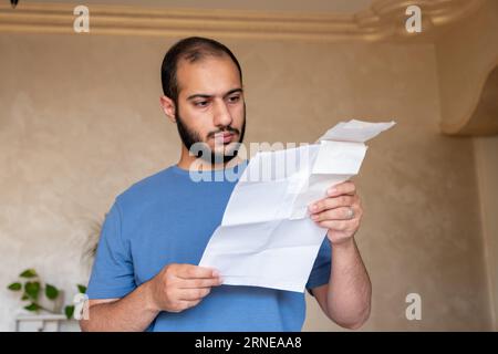 Junger bärtiger Rüde, der mit Gefühlen im Gesicht im Wohnzimmer rezitiert Stockfoto