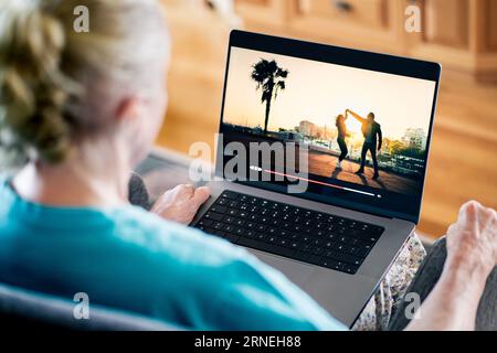 Alte Seniorin, die sich Filme mit Laptop ansieht, während der Stream-Service läuft. TV- oder Serien-On-Demand-Website. Stockfoto