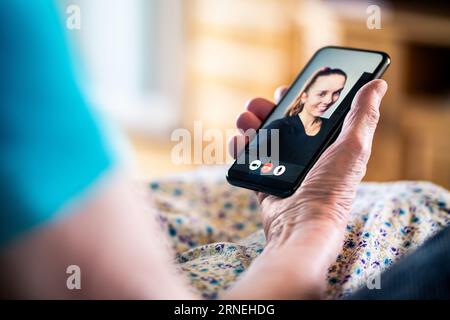 Videoanruf mit der Familie. Mobiltelefonvideokall. Alte ältere Dame und junge Frau. Großmutter und Enkelin sprechen online. Stockfoto