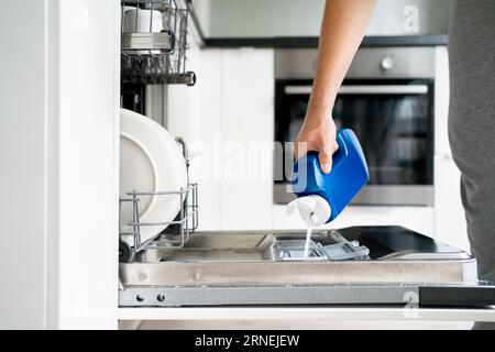 Geschirrspülpulver. Spülmittel und Seife. Man ladet die Waschmaschine. Schmutzige Teller. Haushaltstechnologie für die Hausarbeit. Stockfoto