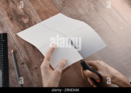 Hände einer älteren Frau falten Origami-Papier. Erstellen eines Origami-Papierkrans, Nahaufnahme Stockfoto