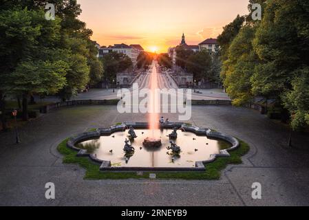 Brunnen mit Wasserstrahlen und Skulpturen auf einem Platz vor der Luitpold-Brücke und Prinzregenten-Straße im Hintergrund des Sonnenuntergangs in München Stockfoto