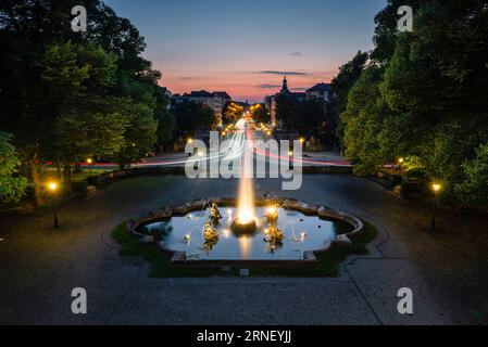 Beleuchteter Brunnen mit Wasserstrahlen und Skulpturen auf einem Platz vor der Luitpold-Brücke und der Prinzregenten-Straße bei Sonnenuntergang in München Stockfoto