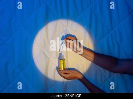 Beruhigende Schlummer: Wissenschaft hinter Schlafölen, Melatonin und Sweet Dreams, Tropfer mit Öl in der Hand Stockfoto