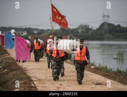 China: Flut bedroht Wuhan (160713) -- WUHAN, 13. Juli 2016 -- bewaffnete Polizeisoldaten bereiten sich auf den Bruch des Damms am Deich des Niushan-Sees in der zentralchinesischen Provinz Hubei vor, 13. Juli 2016. Die Regierung der Provinz Hubei beschloss am Dienstag, den Damm zwischen dem Liangzi Lake und dem Niushan Lake zu brechen, um einen möglichen Überlauf des Deichs zu verhindern. Die Operation wird am 14. Juli durchgeführt. )(wjq) CHINA-HUBEI-LAKE-Flood CONTROL MEASURES (CN) XiaoxYijiu PUBLICATIONxNOTxINxCHN China Flood bedrohte Wuhan 160713 Wuhan 13. Juli 2016 bewaffnete Polizeisoldaten bereiten sich auf den Bruch der Th vor Stockfoto