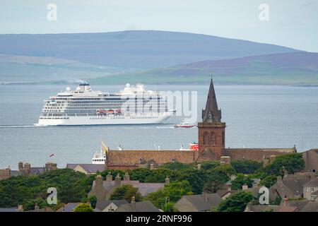 Stromness, Orkney, Schottland, Großbritannien. September 2023. Amerikanische Touristen, die Kreuzfahrtschiffe besuchen, die in Kirkwall anliegen, besuchen den Ring of Brodgar, den neolithischen Steinkreis auf Orkney. Die Einheimischen haben Bedenken geäußert, dass Kreuzfahrtschiffe zu viele Touristen auf die Inseln bringen und die derzeitige Infrastruktur nicht ausreicht. PIC; Kreuzfahrtschiff fährt an der St. Magnus Kathedrale vorbei, wenn es Kirkwall Hafen verlässt. Iain Masterton/Alamy Live News Stockfoto