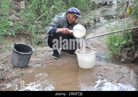 (160824) -- TONGWEI, 24. August 2016 -- Xu Zhiqiang, 68, holt Wasser aus einem Tal in der Nähe von Haus, um Bäume zu bewässern, die auf dem Berg im Dorf Zhangchuan im Tongwei County, nordwestchinesische Provinz Gansu, am 23. August 2016 gepflanzt wurden. Xu Zhiqiang und sein Zwillingsbruder Xu Zhigang haben 48 Jahre lang freiwillig Bäume auf kargen Hügeln auf dem Loess Plateau gepflanzt. Mehr als 350 mu (23 Hektar) karges Land haben sich mit ihrer Plantage von über 80.000 Bäumen und Blumen grün gemacht. Die Bemühungen der Brüder tragen nicht nur dazu bei, natürliche Schönheit zu schaffen, sondern verbessern auch die lokale ökologische Umwelt. Guo Gang) (ry) CHINA-GANSU Stockfoto