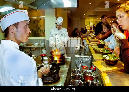 PARIS, Frankreich - mittlere Gruppe Mitarbeiter, Kunden und Restaurantmitarbeiter, im Center, männliche Köche bei der Arbeit in der offenen Küche, chinesisches Innenrestaurant, Le Wok », Restaurantarbeiter, chinesischer Migrant Stockfoto