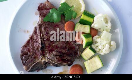 Saftiges Steak mit Hülsenfrüchten auf dem Teller, Blick von oben auf das Fleisch mit Blumenkohl, Karotten, Zucchini. Köstliches, proteinreiches Essen Stockfoto