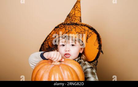 Halloween-Kind mit Zauberhut und Kürbis. Niedlicher Junge mit Hexenhut und Halloween Jack-o-Laterne. Halloween-Feiertagsfeier. Trick oder Belohnung. Wenig Stockfoto