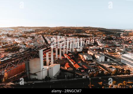 Horizontale Luftaufnahme von Straßen und Gebäuden Lissabons bei Sonnenuntergang. Die Brücke vom 25. april in Libson mit historischem Stadtzentrum und Dächern von abo Stockfoto