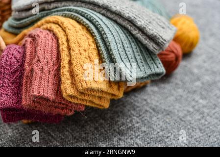 Handgestrickte Wollsocken in verschiedenen Farben auf grauem Hintergrund Stockfoto