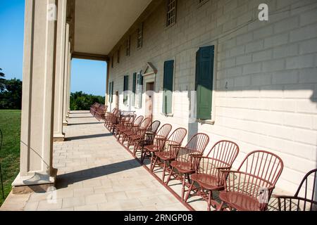 ALEXANDRIA, Virginia, USA – Eine Reihe von Windsor-Stühlen säumt den Innenhof vor dem Hauptgebäude von Mount Vernon, dem historischen Wohnhaus von George Washington, in Alexandria, Virginia. Die Stühle blicken auf das weitläufige Gelände des Anwesens und den Potomac River dahinter. Stockfoto