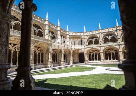 Kloster Mosteiro dos Jeronimos Belem Portugal // BELEM, Portugal — kunstvolle zweistöckige Kreuzgänge säumen den Innenhof von Mosteiro dos Jeronimos, ein UNESCO-Weltkulturerbe und Meisterwerk der Manuelinischen Architektur. Das Kloster, auch bekannt als Hieronymitenkloster, wurde im frühen 16. Jahrhundert von König Manuel I. beauftragt, Vasco da Gama's erfolgreiche Reise nach Indien zu gedenken. Der Bau begann um 1501 und wurde fast ein Jahrhundert lang fortgesetzt, wobei kunstvolle Steinschnitzereien und maritime Motive verwendet wurden, die für Portugals Zeitalter der Entdeckung charakteristisch sind. Die Kreuzgänge sind mit komplizierten Sc Stockfoto