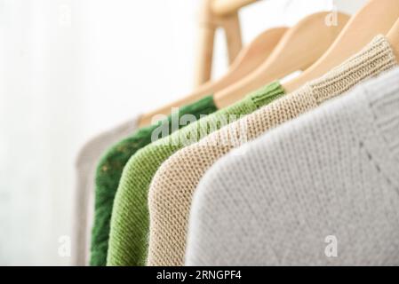 Bunte, handgestrickte Pullover auf Kleiderbügeln in Nahaufnahme. Modekonzept. Stockfoto