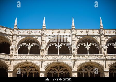 Kloster Mosteiro dos Jeronimos Belem Portugal // BELEM, Portugal — kunstvolle zweistöckige Kreuzgänge säumen den Innenhof von Mosteiro dos Jeronimos, ein UNESCO-Weltkulturerbe und Meisterwerk der Manuelinischen Architektur. Das Kloster, auch bekannt als Hieronymitenkloster, wurde im frühen 16. Jahrhundert von König Manuel I. beauftragt, Vasco da Gama's erfolgreiche Reise nach Indien zu gedenken. Der Bau begann um 1501 und wurde fast ein Jahrhundert lang fortgesetzt, wobei kunstvolle Steinschnitzereien und maritime Motive verwendet wurden, die für Portugals Zeitalter der Entdeckung charakteristisch sind. Die Kreuzgänge sind mit komplizierten Sc Stockfoto