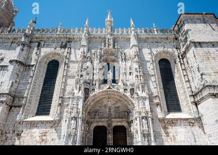 Kloster Jeronimos Haupteingang Manueline Kalksteinfassade Belem Lissabon Portugal / BELÉM, Lissabon, Portugal — der Haupteingang und die Fassade des Mosteiro dos Jerónimos (Kloster Jerónimos) zeigen den Manuelinstil in seiner monumentalsten Form, den Kalkstein mit maritimen Motiven, religiösen Figuren, botanischen Ornamenten und das Armillarsphäriemblem von König Manuel I. Manuel I. beauftragte das Kloster 1501–1502, für die erfolgreiche Öffnung der Seeroute nach Indien durch Vasco da Gama zu danken, die Mönche des Ordens des Heiligen Jerome und die Finanzierung spendete Stockfoto