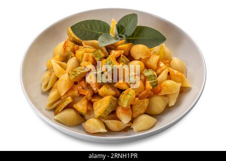 Conchiglie Rigate Pasta. Makkaroni in Form einer geriffelten Schale mit Zucchini und Tomatensauce mit Salbeiblättern in weißem Gericht, isoliert auf weiß mit Clipp Stockfoto