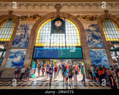 Porto, Portugal, Europa - 26. Juni 2023: Innenansicht des berühmten Bahnhofs und des Bahnsteigs, mit Touristen, die sich bereit machen und das ti konsultieren Stockfoto