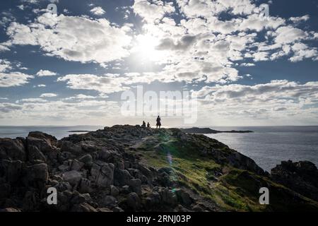 Reisende, die ein Foto mit einem Handy an einer felsigen Küste mit Blick auf den Atlantik in Neufundland Kanada machen. Stockfoto