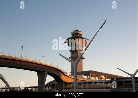 Ein Flugzeug, das von LAX abfliegt, fliegt über neu installierte Gleise für die Metro Rail-Linie, vorbei am berühmten Theme Building und Kontrollturm in L.A., CA. Stockfoto