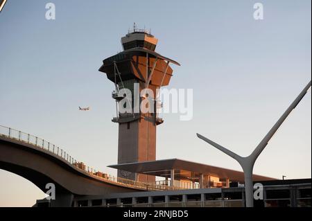 Ein abfliegendes Flugzeug fliegt am Kontrollturm am Flughafen LAX vorbei und über Gleise, die zu einem Bahnhof für Metro Rail-Passagiere in Los Angeles, CA, USA führen Stockfoto